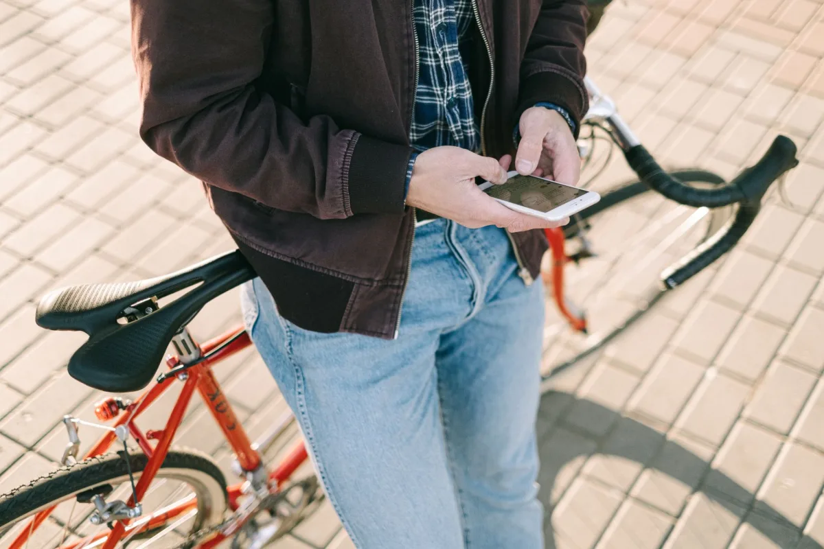 Person leaning on road bike using smartphone outdoors during the day. Person leaning on road bike using smartphone outdoors during the day.