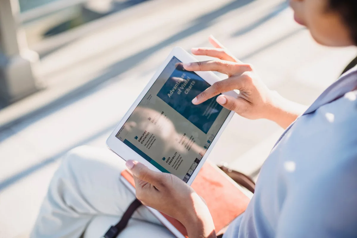 A woman using a tablet outside, browsing in natural light. A woman using a tablet outside, browsing in natural light.