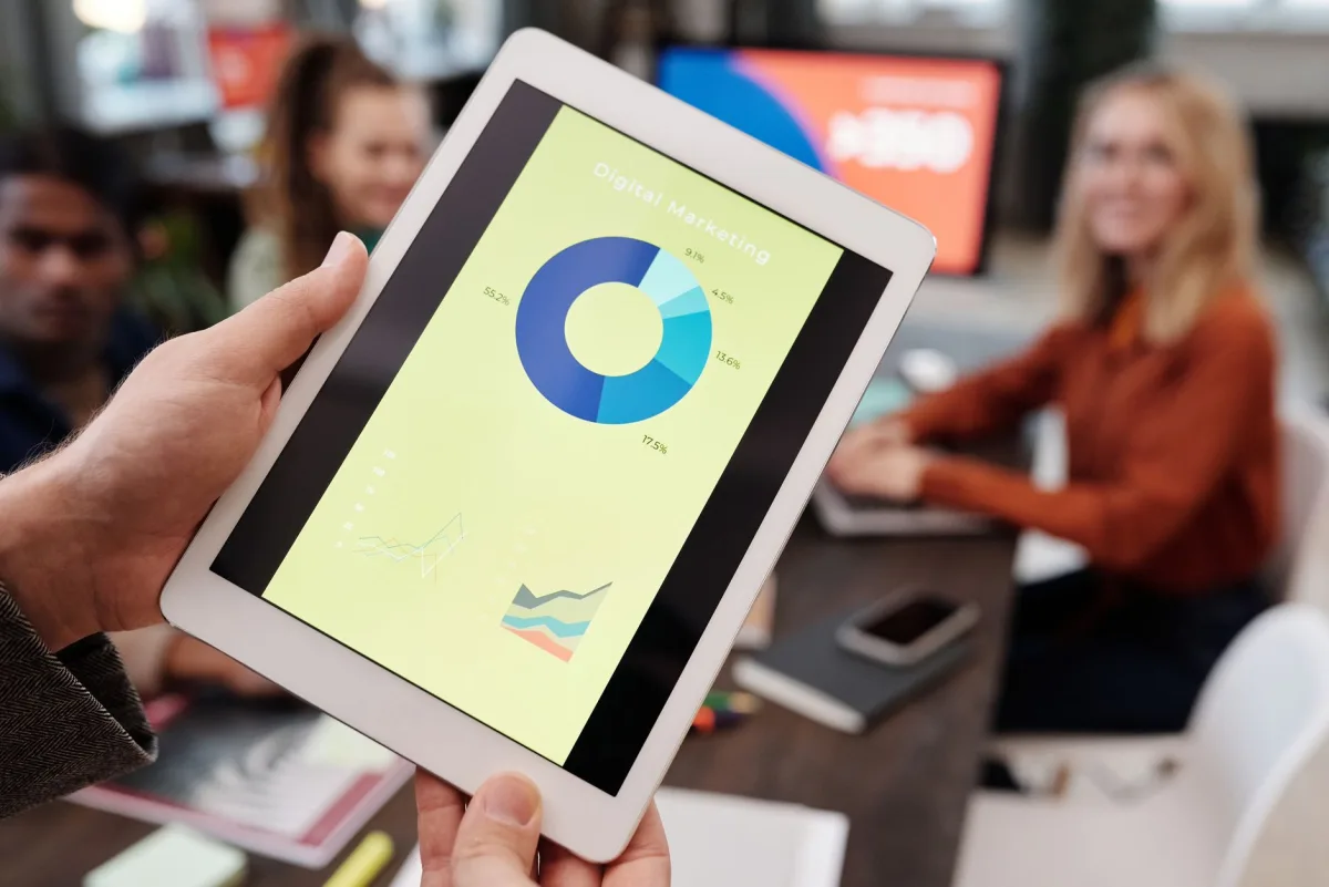 Business team reviewing marketing statistics on a tablet during an indoor meeting. Business team reviewing marketing statistics on a tablet during an indoor meeting.
