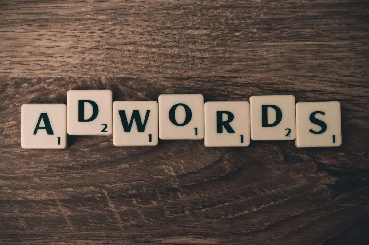 Scrabble tiles spelling 'AdWords' on a wooden surface, symbolizing marketing concepts.