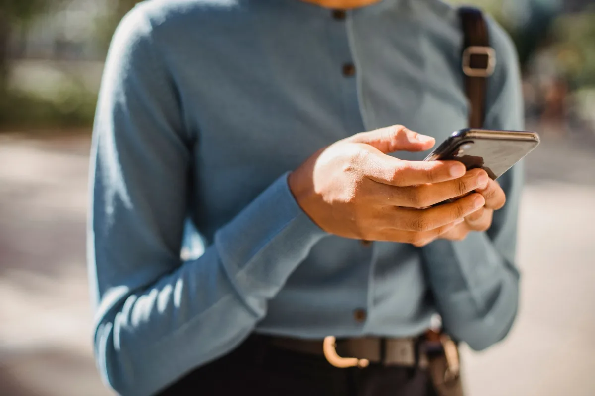 Close-up of a person using a smartphone outdoors, focusing on hands and mobile device. Close-up of a person using a smartphone outdoors, focusing on hands and mobile device.