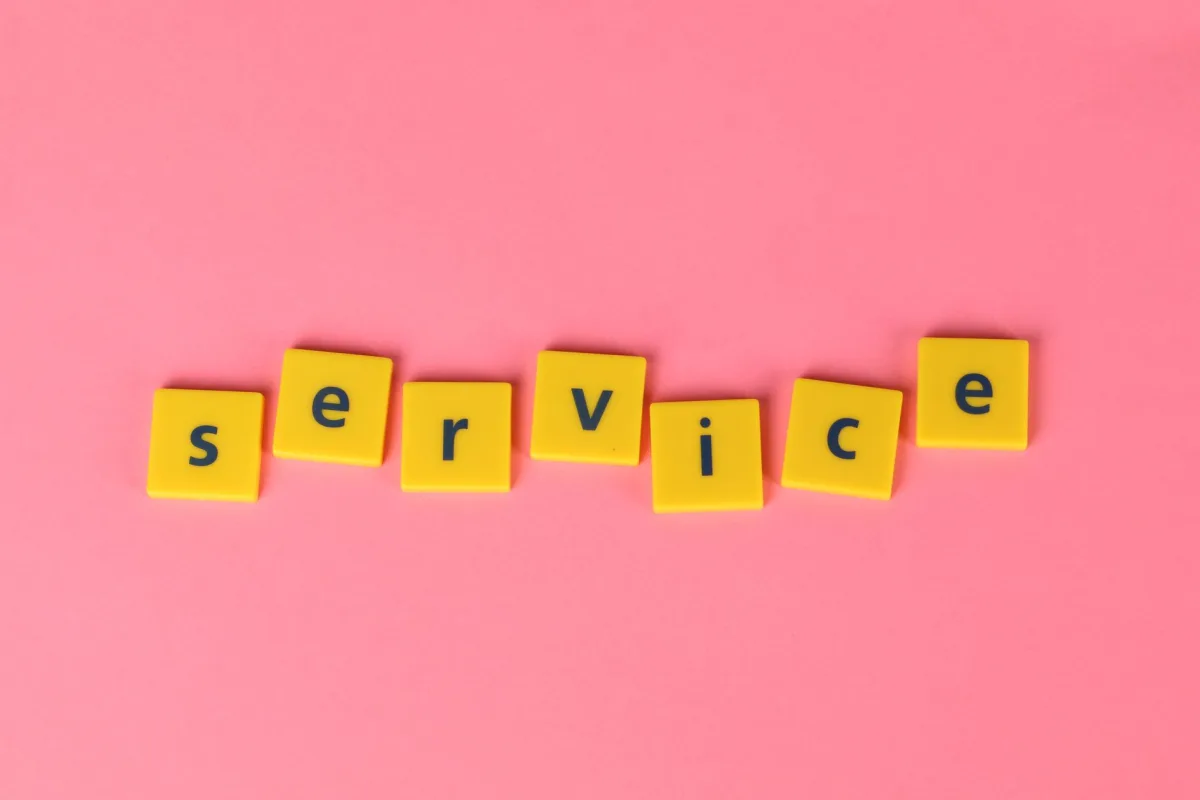 Yellow tiles spelling the word 'service' on a pink background, visually appealing design.