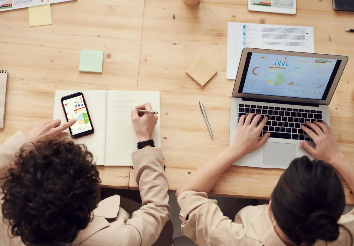 Overhead shot of two colleagues collaborating with devices and notes in a business meeting. Overhead shot of two colleagues collaborating with devices and notes in a business meeting.