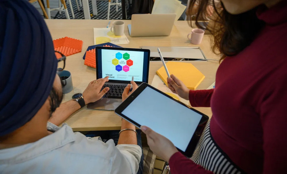 Creative meeting with devices in a modern office, showcasing teamwork and collaboration.