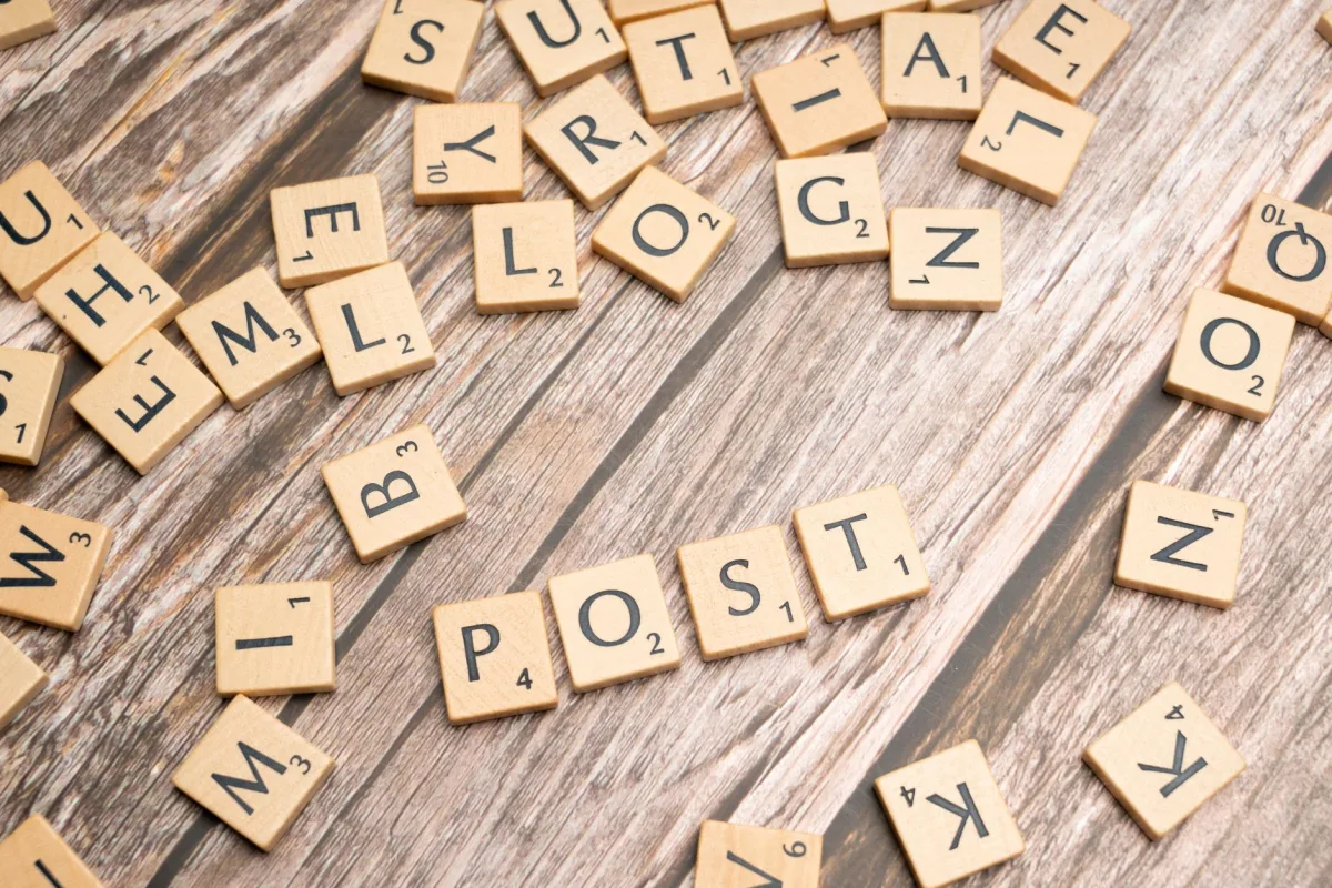 Wooden scrabble tiles scattered with the word 'POST' on a rustic wooden surface.