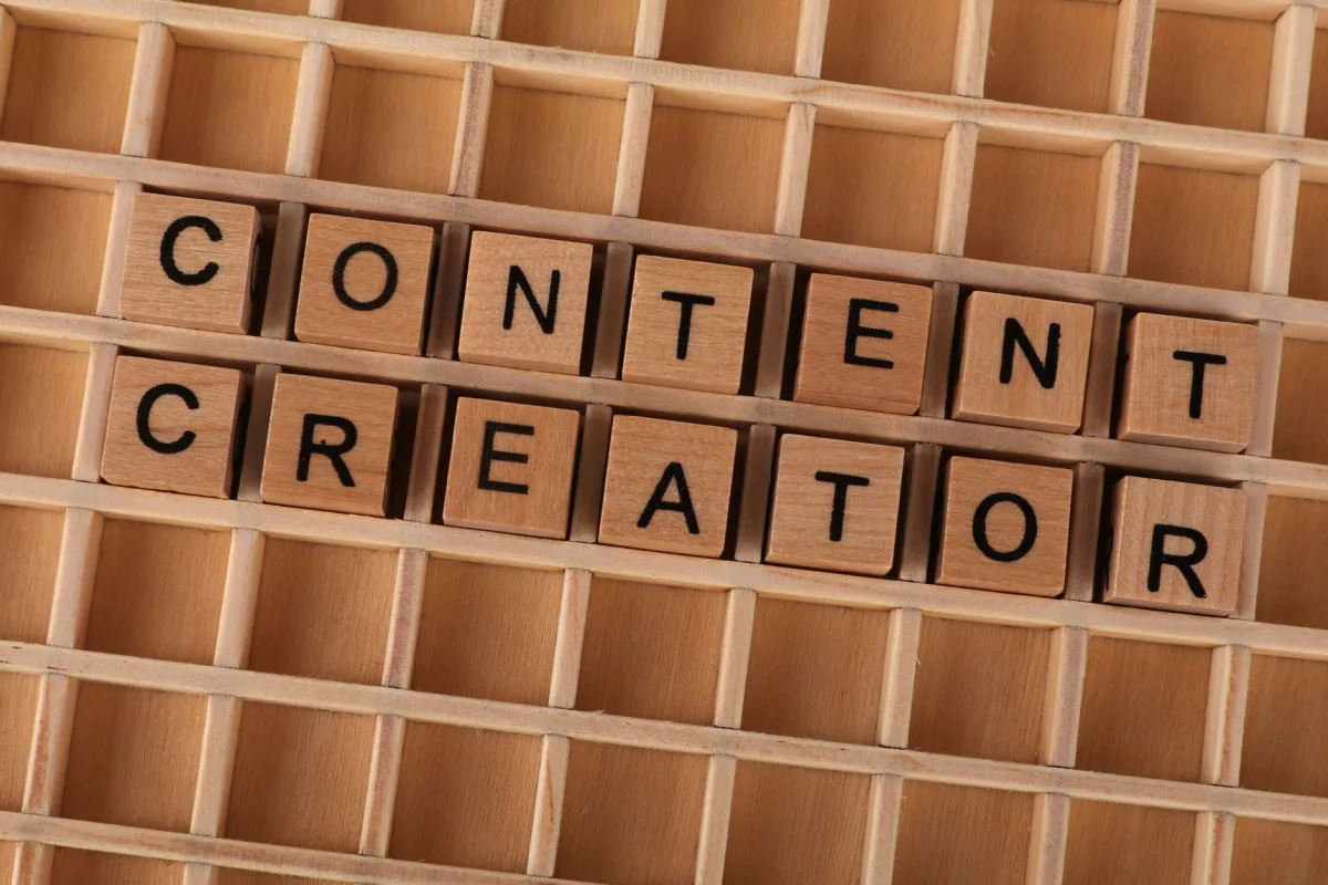 Wooden block letters spelling 'Content Creator' on a grid background. Ideal for marketing themes. Wooden block letters spelling 'Content Creator' on a grid background. Ideal for marketing themes.