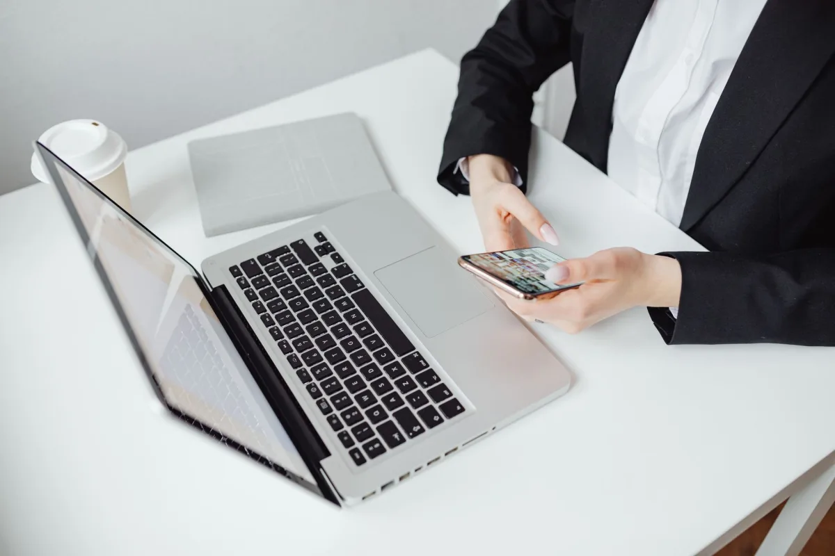 Businesswoman using smartphone at desk with laptop and coffee cup. Businesswoman using smartphone at desk with laptop and coffee cup.
