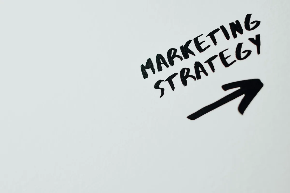 Close-up of handwritten 'Marketing Strategy' text with an arrow on white background. Close-up of handwritten 'Marketing Strategy' text with an arrow on white background.