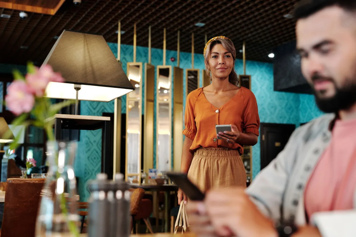 Two adults using smartphones in a trendy restaurant with colorful decor.