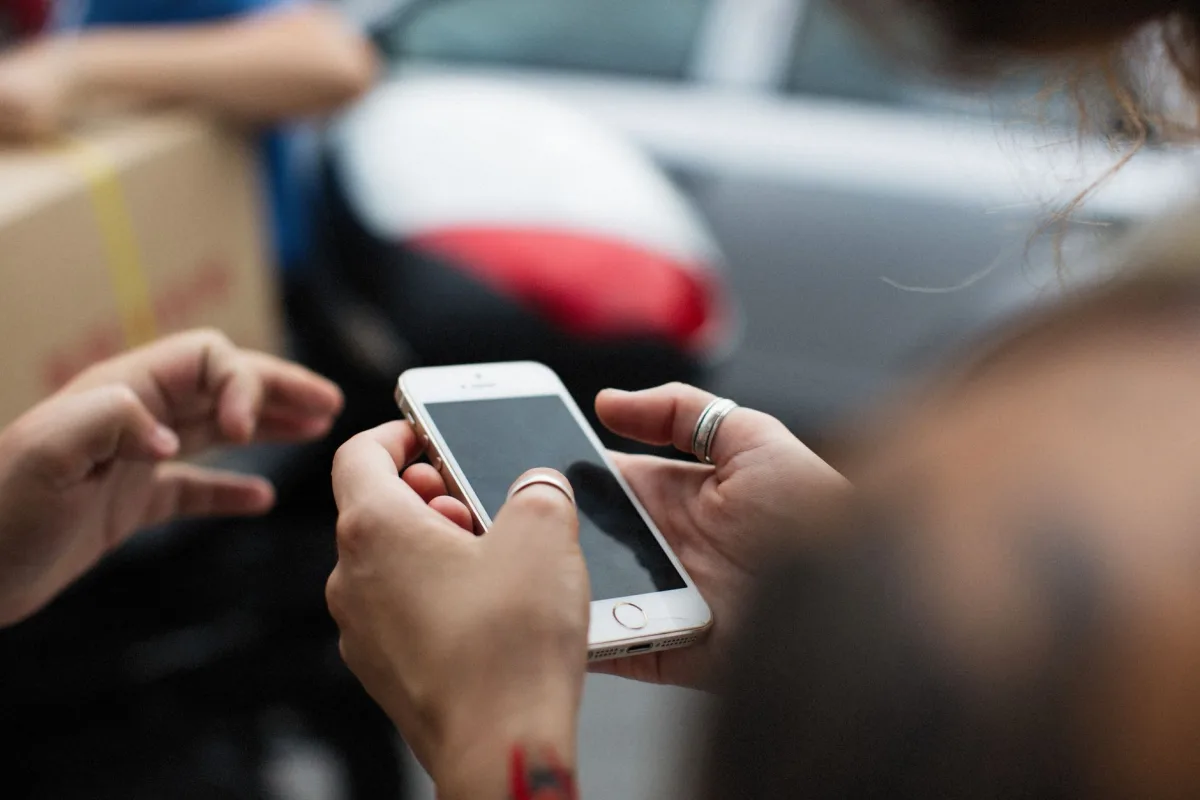Hands holding a smartphone outdoors, showcasing technology in everyday life.