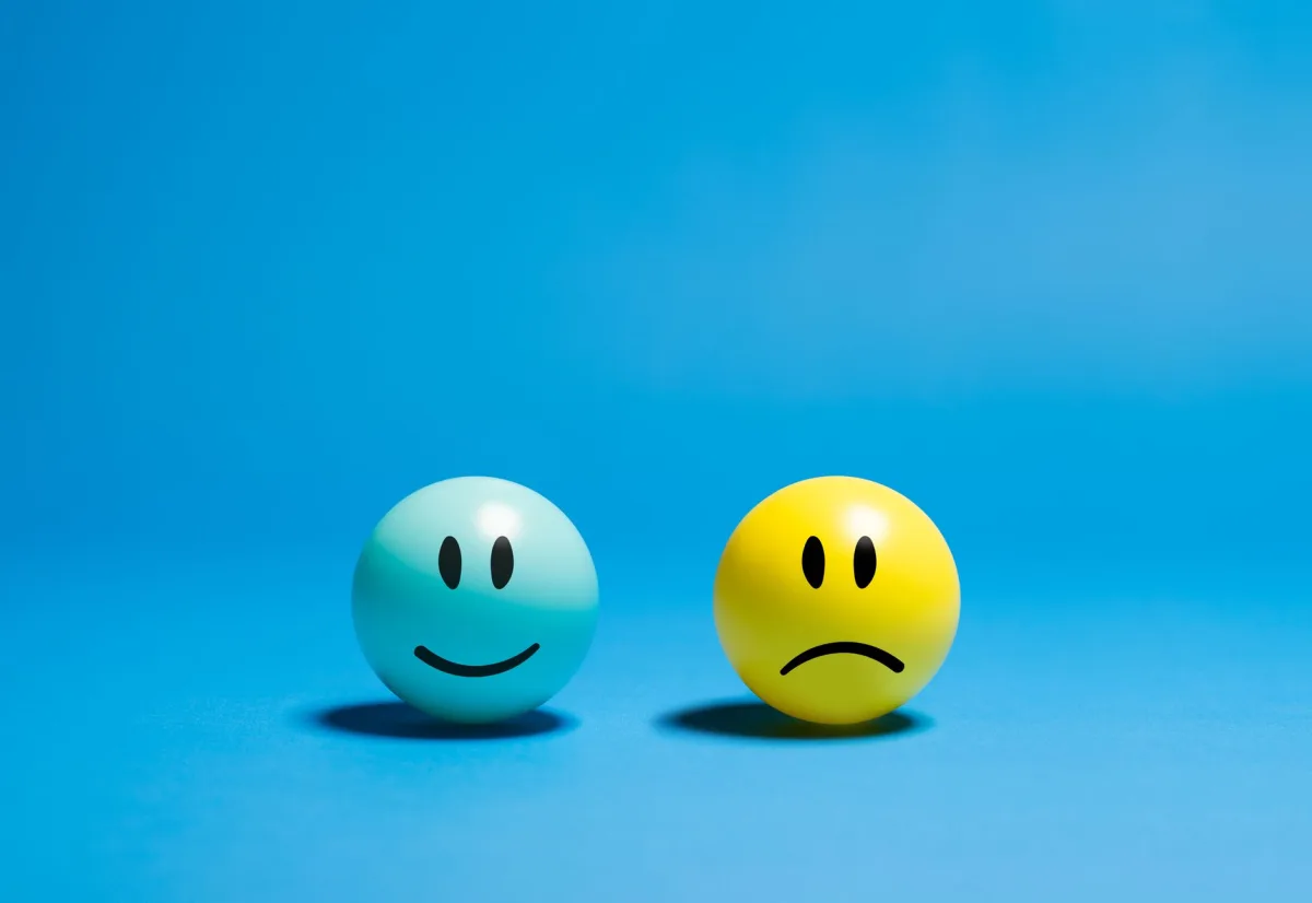 Two smiley balls representing opposite emotions on a blue background. Two smiley balls representing opposite emotions on a blue background.