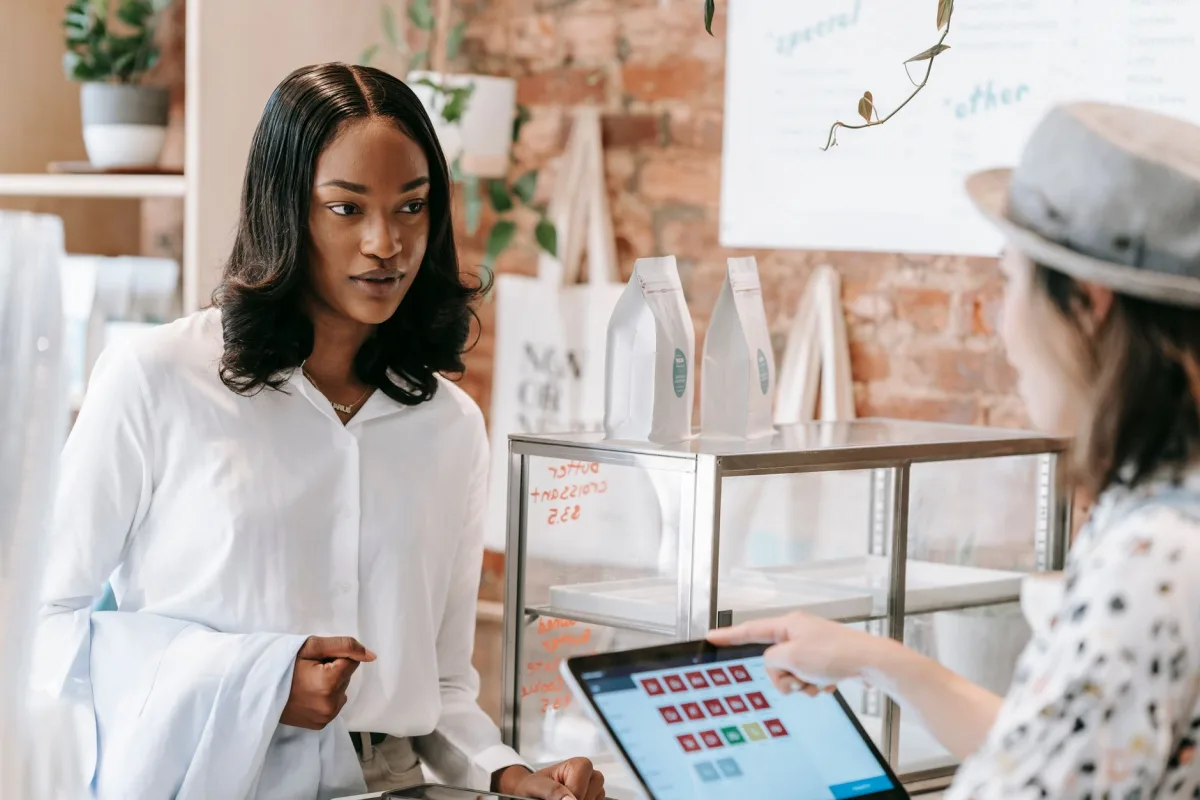 A interacts with a barista at a trendy coffee shop counter, showcasing modern retail service. A interacts with a barista at a trendy coffee shop counter, showcasing modern retail service.