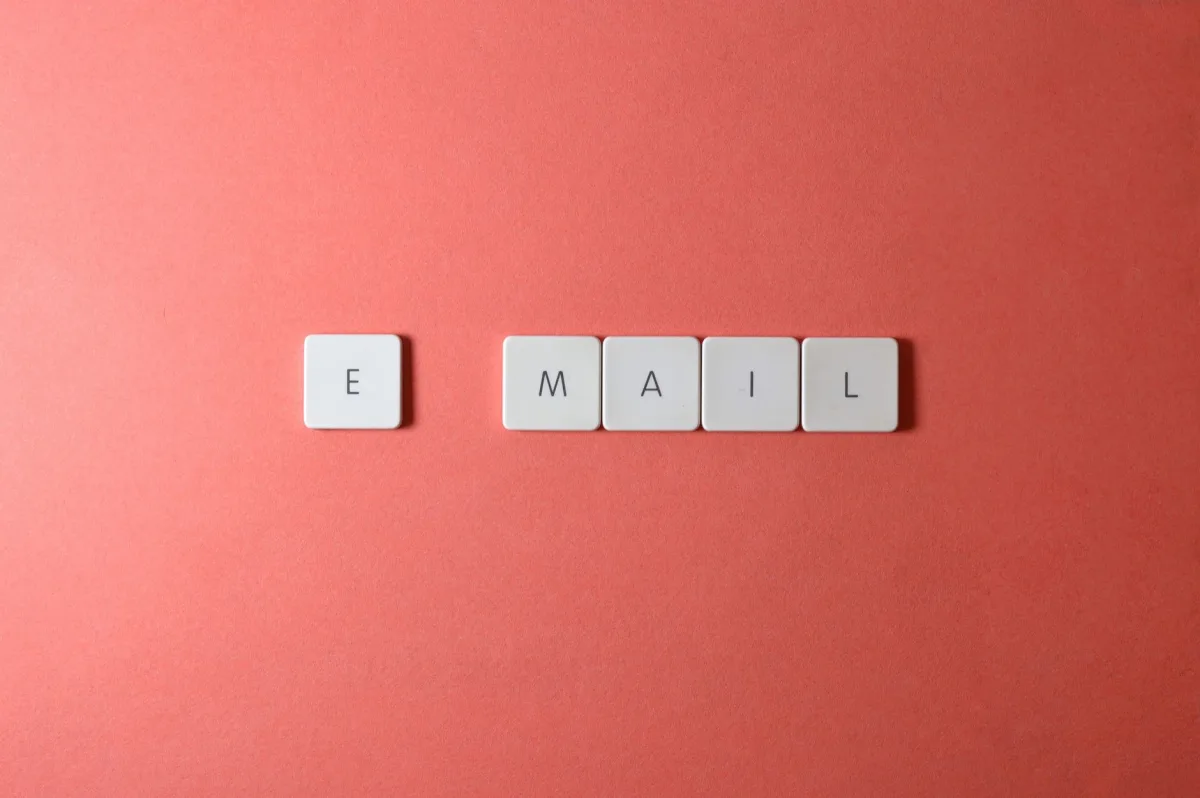 Flat lay of keyboard letter tiles spelling 'email' on coral backdrop. Flat lay of keyboard letter tiles spelling 'email' on coral backdrop.