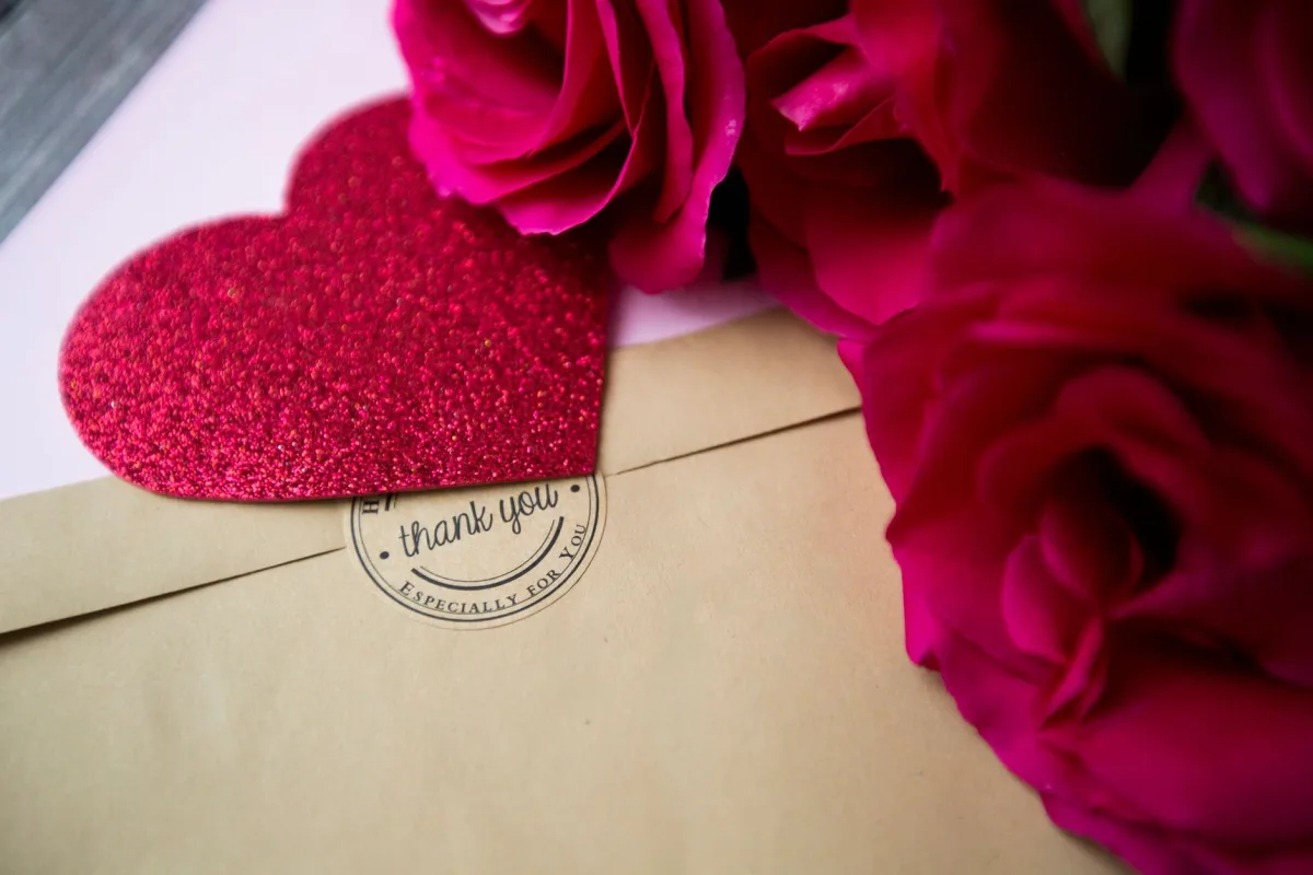 Close-up of red roses, card, and a heart, symbolizing love and gratitude.