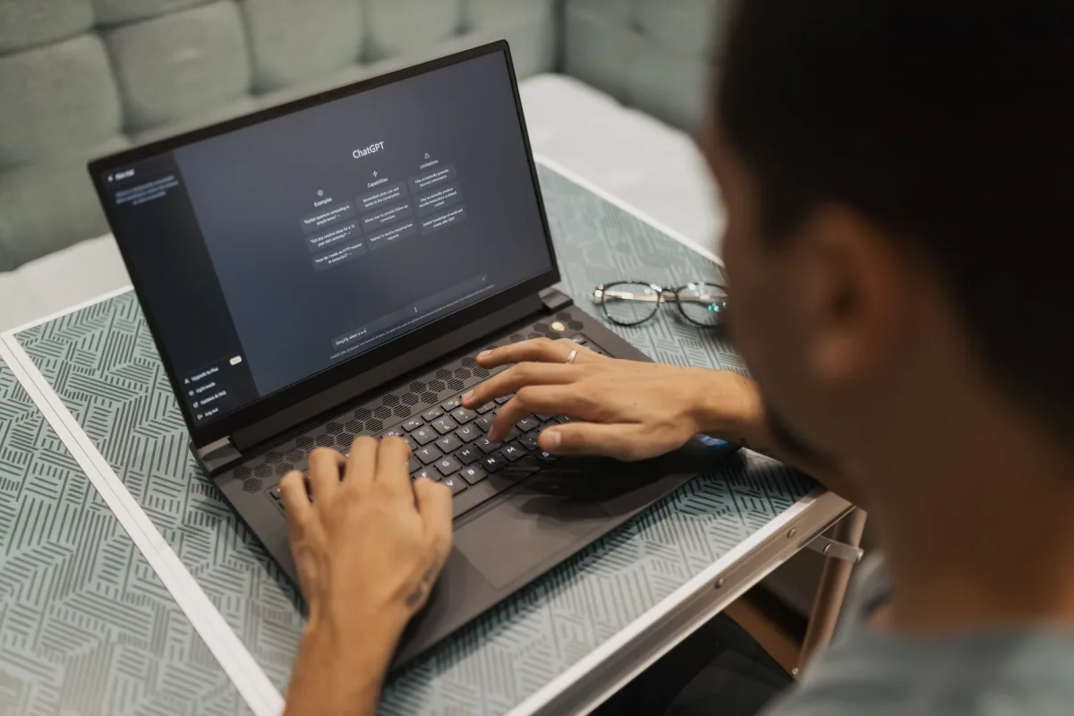 A person using a laptop to interact with AI technology indoors during the day. A person using a laptop to interact with AI technology indoors during the day.