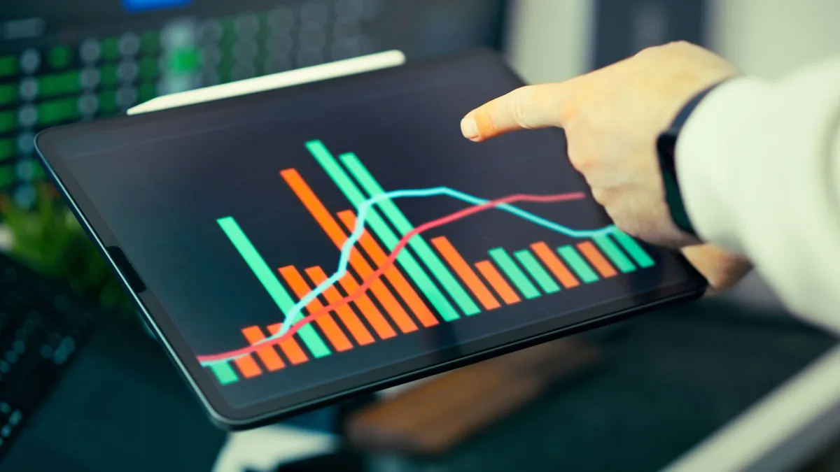 A person analyzing business data with colorful graphs on a tablet screen. A person analyzing business data with colorful graphs on a tablet screen.