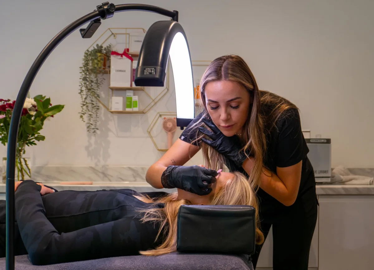 Beauty technician applying eyelash extensions to a client in a modern salon setting. Beauty technician applying eyelash extensions to a client in a modern salon setting.