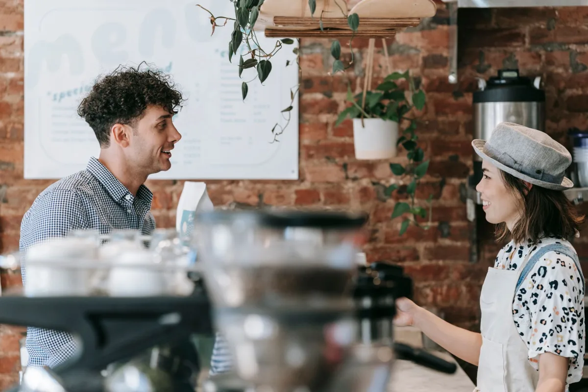 Smiling barista engaging in conversation with a in a cozy coffee shop. Smiling barista engaging in conversation with a in a cozy coffee shop.