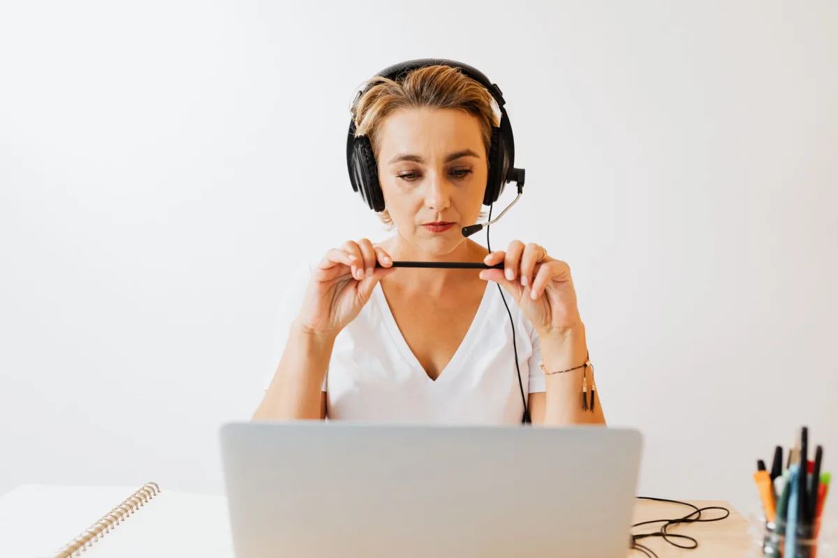 Adult woman in headphones using laptop for remote work in a home office setting. Adult woman in headphones using laptop for remote work in a home office setting.