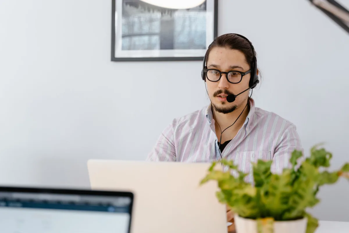 Focused man with headset working on a laptop in a modern home office setting. Focused man with headset working on a laptop in a modern home office setting.