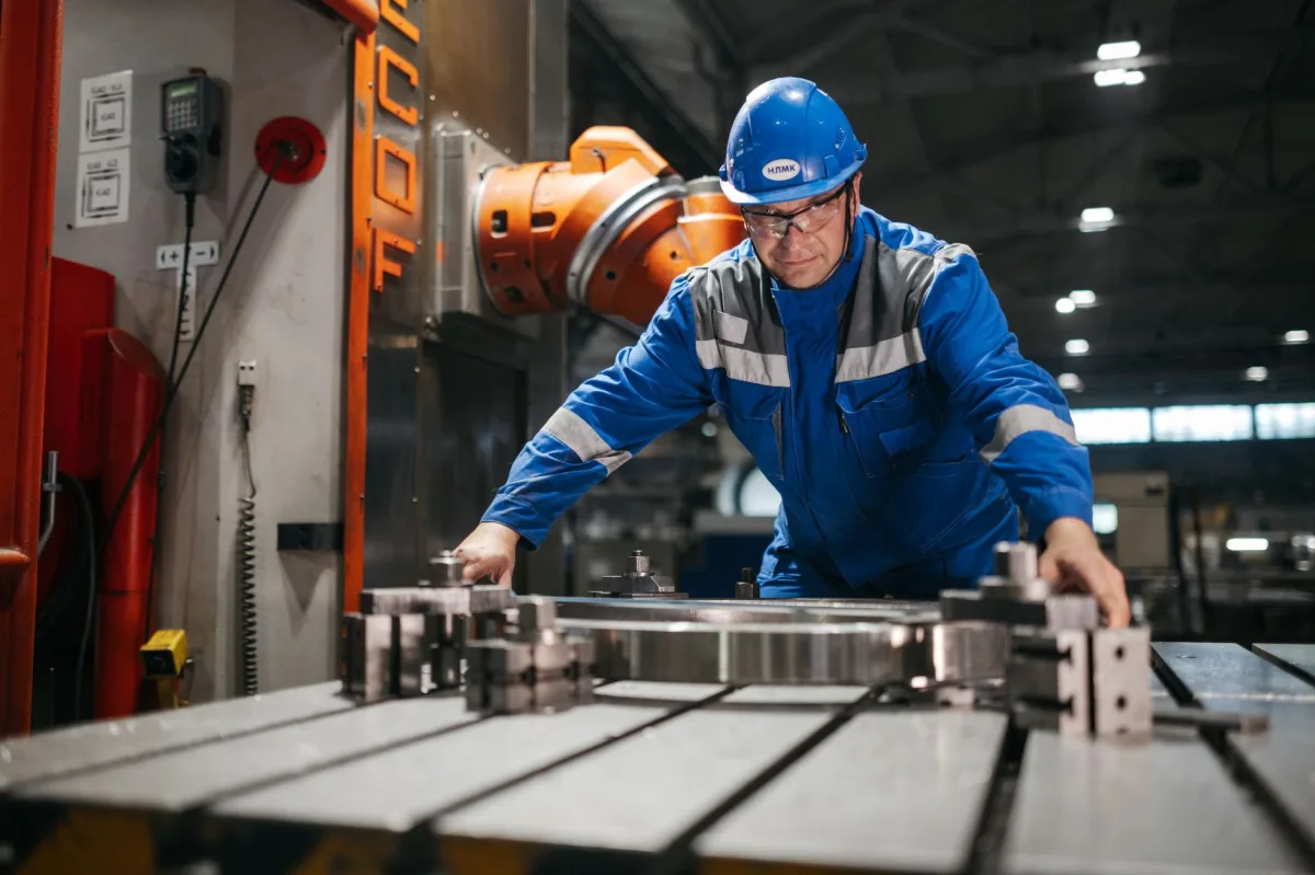 Male worker in blue uniform operates machinery in an industrial factory setting, showcasing engineering and industry.