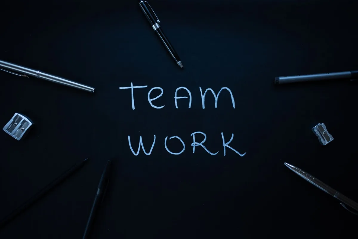 Arrangement of office supplies around teamwork text on black background. Arrangement of office supplies around teamwork text on black background.