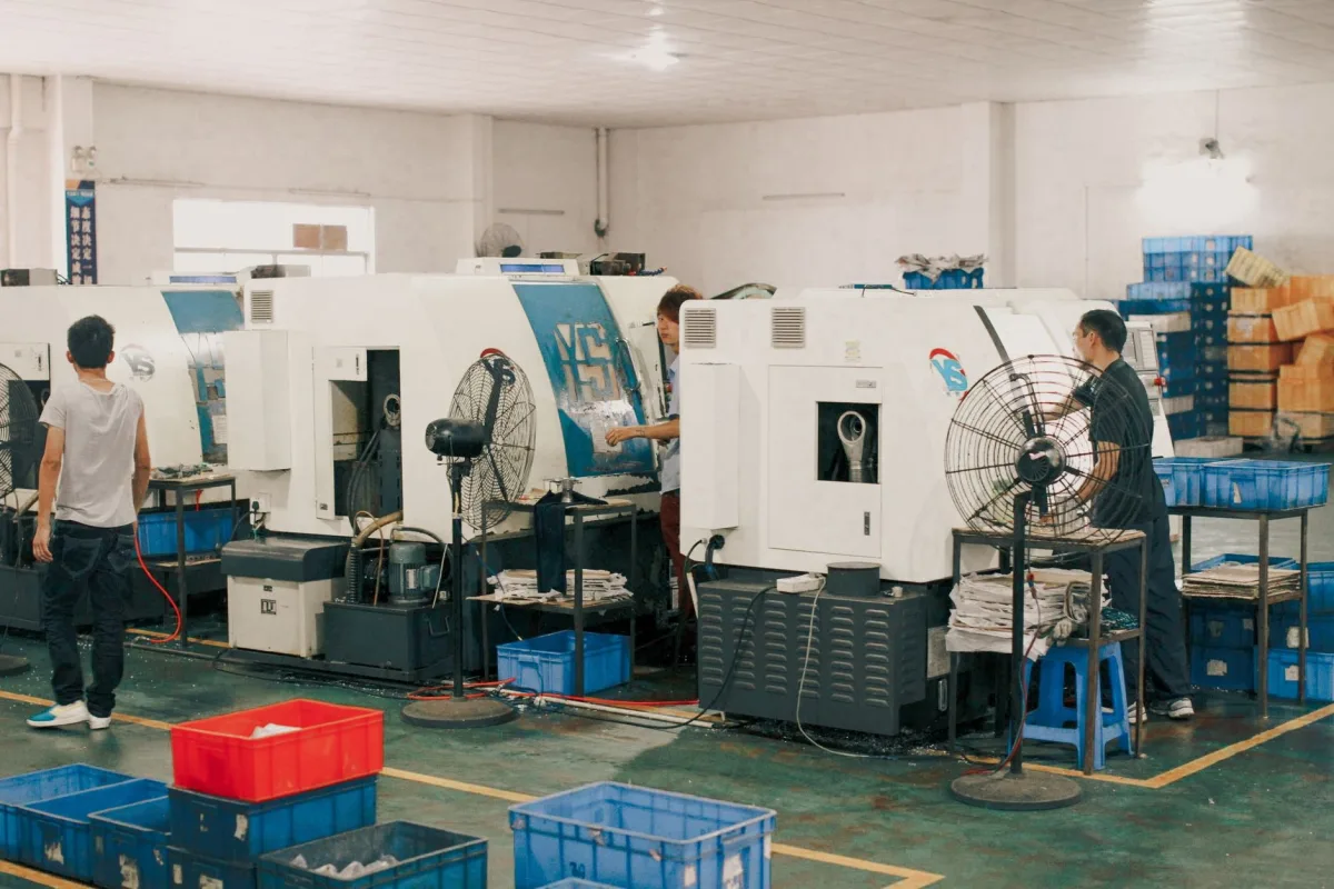 Workers operating machinery in an industrial factory setting, showcasing manual labor and production. Workers operating machinery in an industrial factory setting, showcasing manual labor and production.