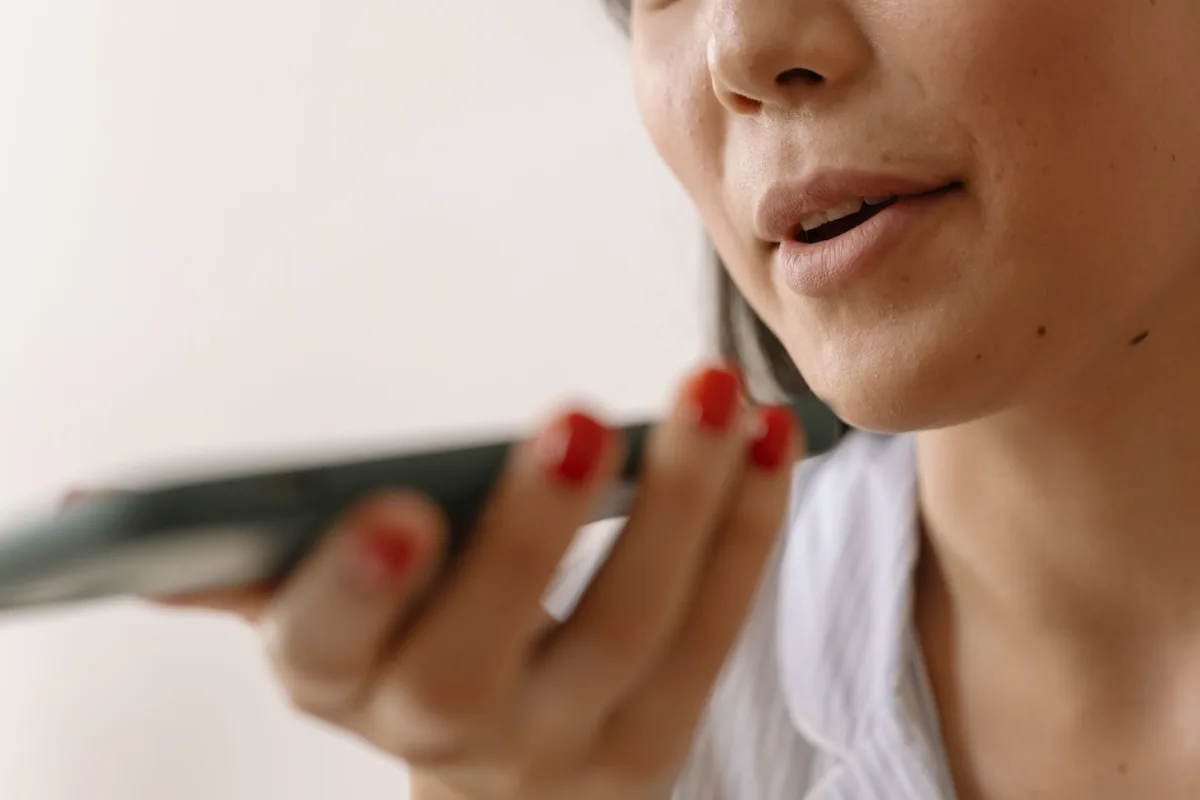 Close-up of a woman using smartphone voice command, showcasing technology and communication. Close-up of a woman using smartphone voice command, showcasing technology and communication.