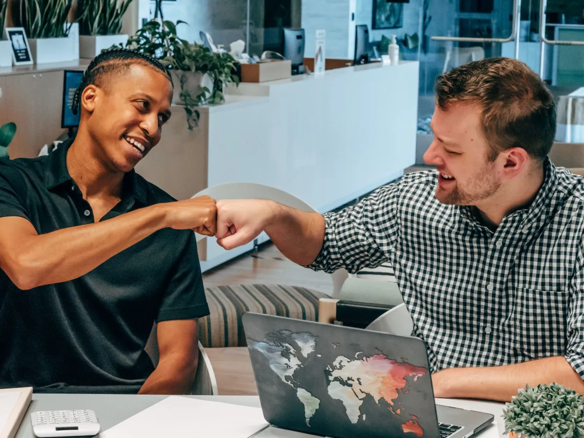 Two colleagues exchange a fist bump in a modern office. Collaborative and friendly work environment. Two colleagues exchange a fist bump in a modern office. Collaborative and friendly work environment.