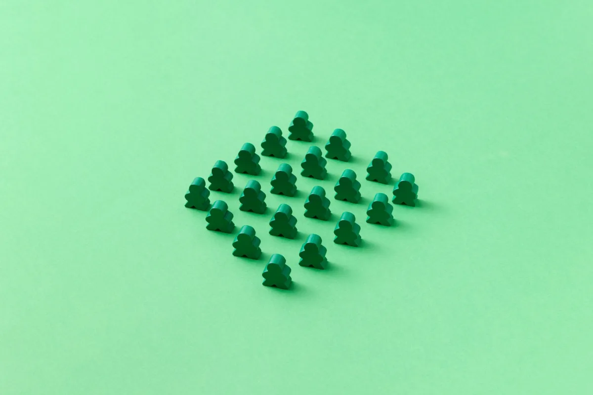 Green meeples arranged neatly on a green background, showcasing minimalist design and pattern. Green meeples arranged neatly on a green background, showcasing minimalist design and pattern.
