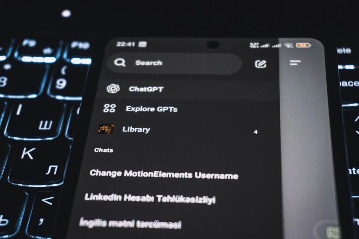 Close-up of a smartphone displaying a chat app interface with a backlit keyboard in the background.