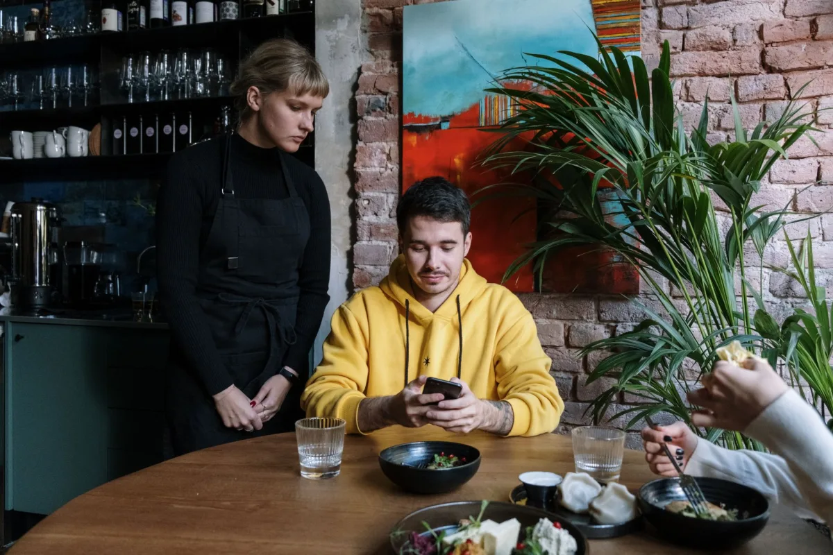 Two people interacting in a stylish café with art and greenery. Two people interacting in a stylish café with art and greenery.