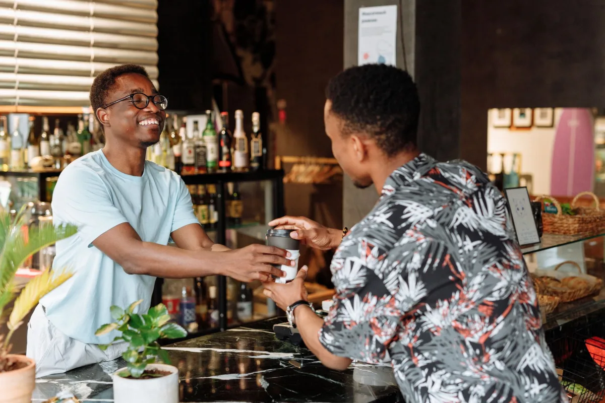Smiling receives a takeaway coffee from a cheerful barista in a lively cafe.
