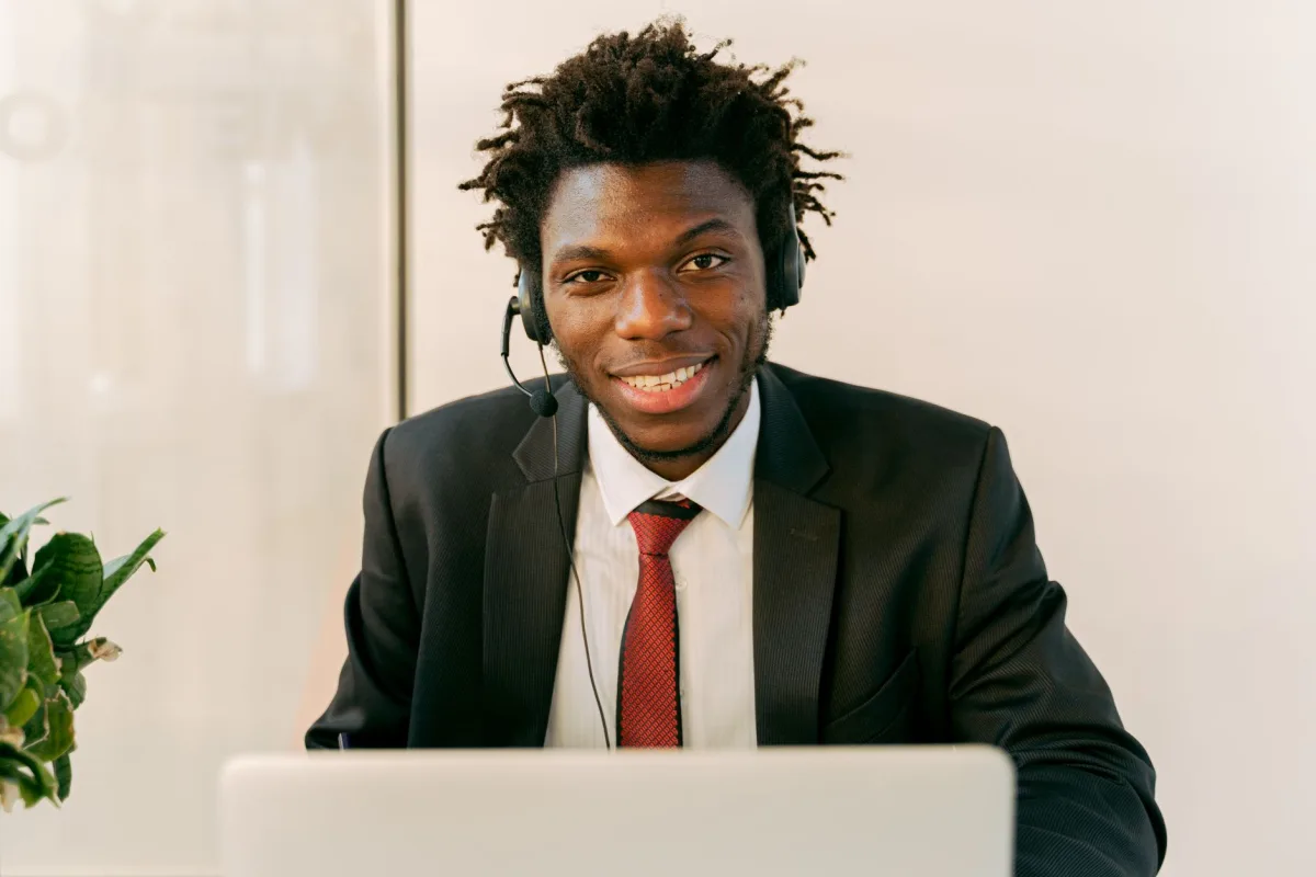 Confident businessman in a suit with a headset, working on a laptop in a modern office. Confident businessman in a suit with a headset, working on a laptop in a modern office.