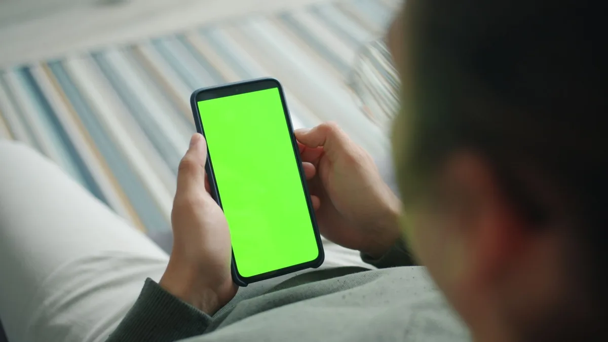 Close-up of person using phone with green screen for custom content display. Close-up of person using phone with green screen for custom content display.