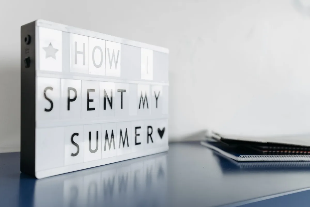 Close-up of a lightbox with 'How I Spent My Summer' text on a desk.