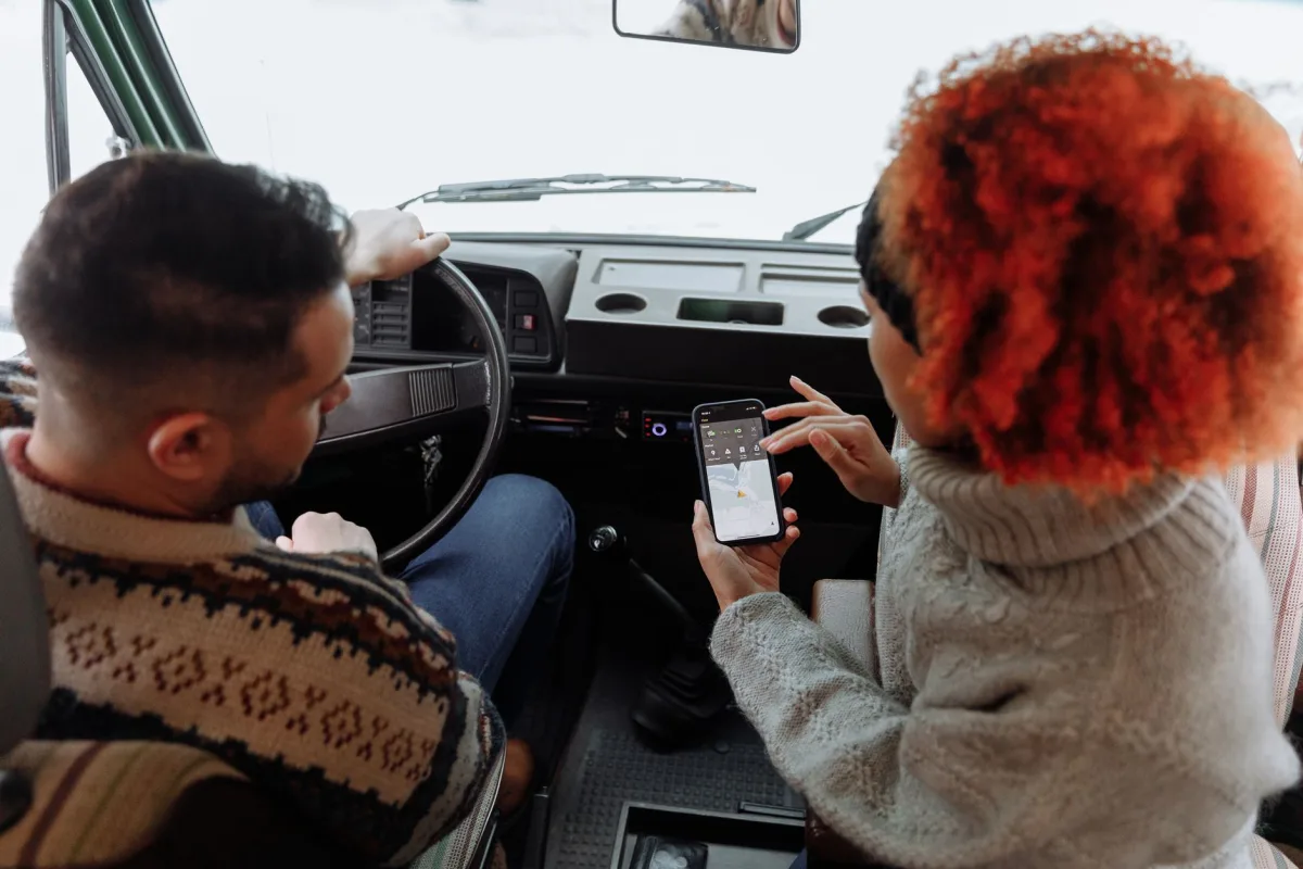 A couple using smartphone navigation while traveling in a van during winter.
