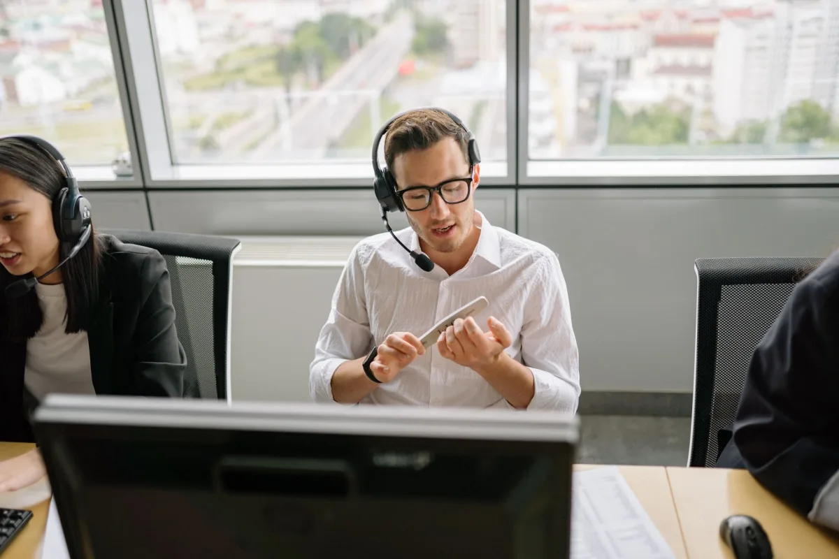 Call center agents wearing headsets and working at their desks in a modern office setting. Call center agents wearing headsets and working at their desks in a modern office setting.