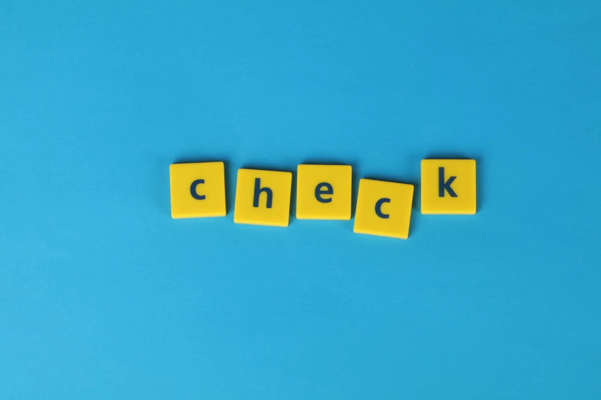Yellow letter tiles spelling 'check' on a vibrant blue background, conveying approval or verification. Yellow letter tiles spelling 'check' on a vibrant blue background, conveying approval or verification.
