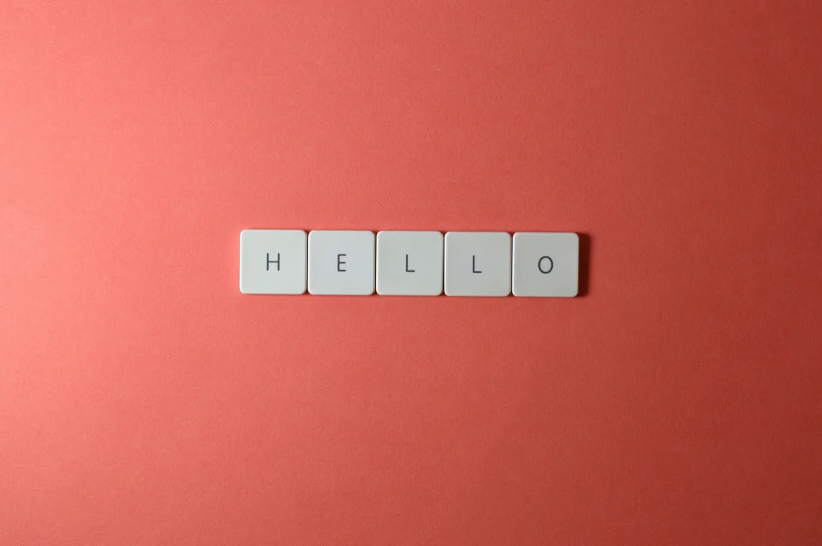 Simple 'Hello' in white letter tiles on a coral background for communication concepts. Simple 'Hello' in white letter tiles on a coral background for communication concepts.