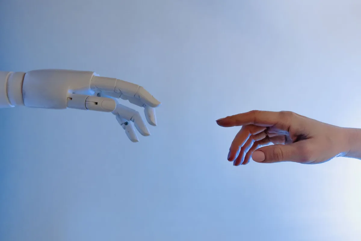 A hand reaching towards a robotic hand symbolizing technology connection. A hand reaching towards a robotic hand symbolizing technology connection.