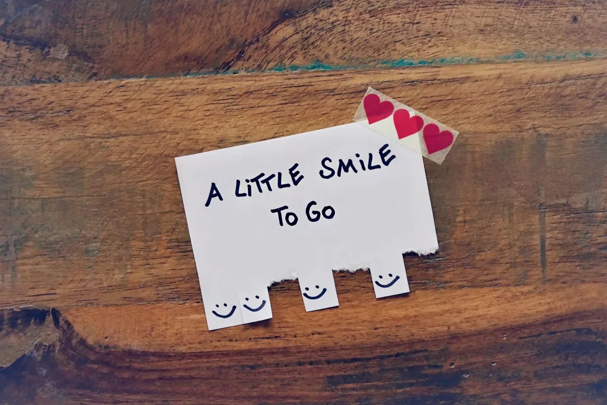A charming handwritten note with tear-off smiley slips on a wooden surface. A charming handwritten note with tear-off smiley slips on a wooden surface.