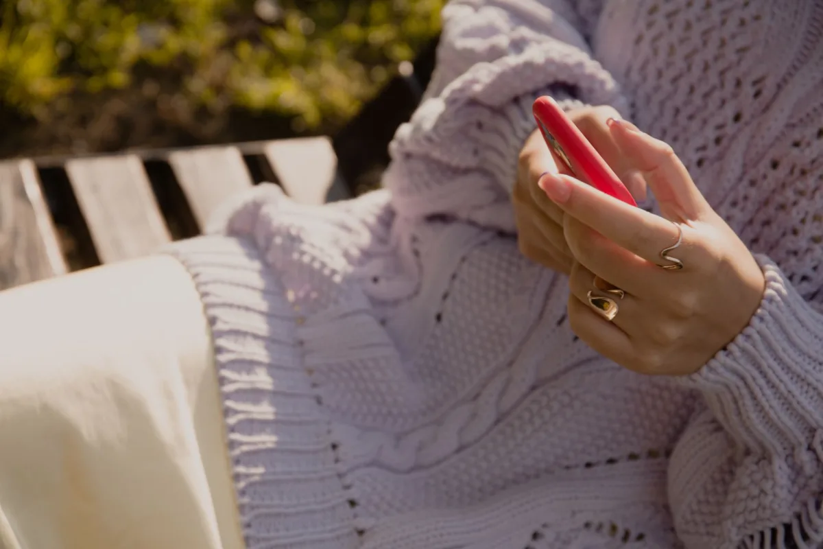 Close-up of hands holding a smartphone outdoors in a cozy setting. Close-up of hands holding a smartphone outdoors in a cozy setting.