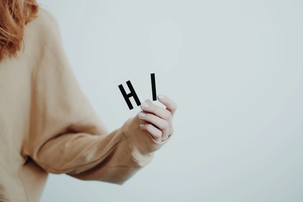 Close-up of a hand holding letters spelling 'Hi' in a minimalist style. Close-up of a hand holding letters spelling 'Hi' in a minimalist style.
