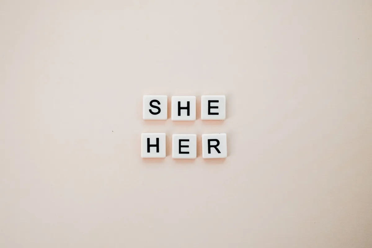 Minimalist photo of letter tiles spelling She Her on a neutral background. Minimalist photo of letter tiles spelling She Her on a neutral background.