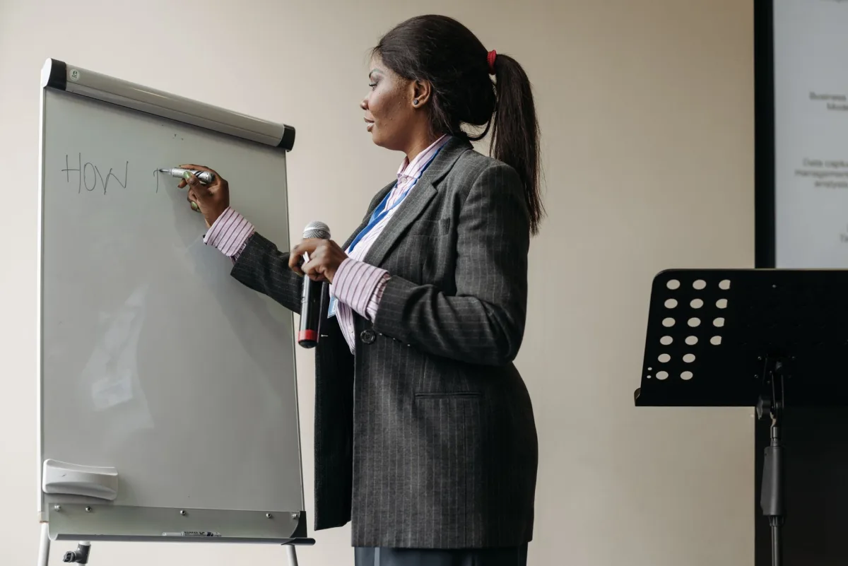 Confident businesswoman presenting ideas on a whiteboard during a seminar. Confident businesswoman presenting ideas on a whiteboard during a seminar.