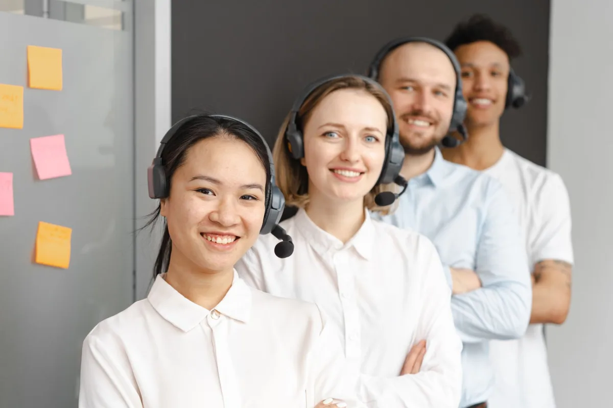 Smiling service team wearing headsets in an office setting, ready to assist clients.