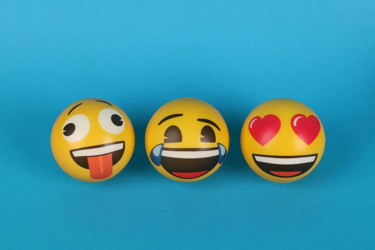 Three playful emoji balls with different expressions on a blue background. Three playful emoji balls with different expressions on a blue background.