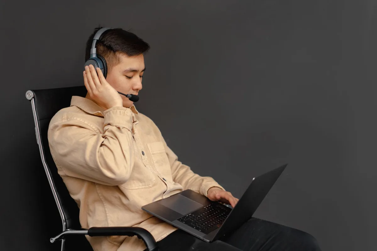 Portrait of an Asian man wearing a headset and working on a laptop. Ideal for customer service concepts.