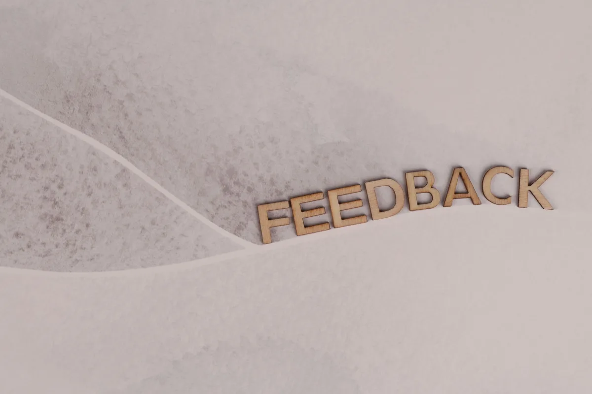 Wooden letters spelling 'FEEDBACK' arranged on textured paper background, conveying a conceptual theme. Wooden letters spelling 'FEEDBACK' arranged on textured paper background, conveying a conceptual theme.